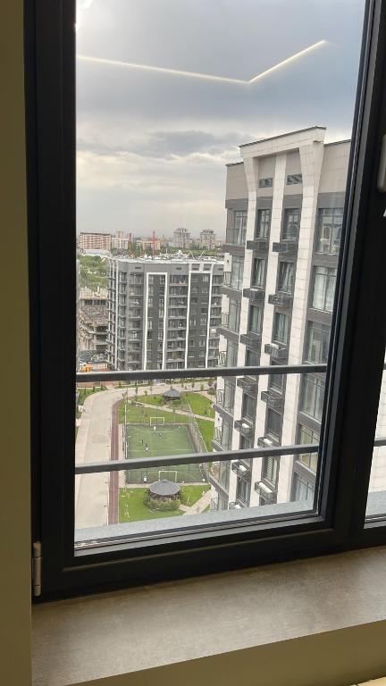 een raam met uitzicht op een groot gebouw bij 13 mountains in Bisjkek