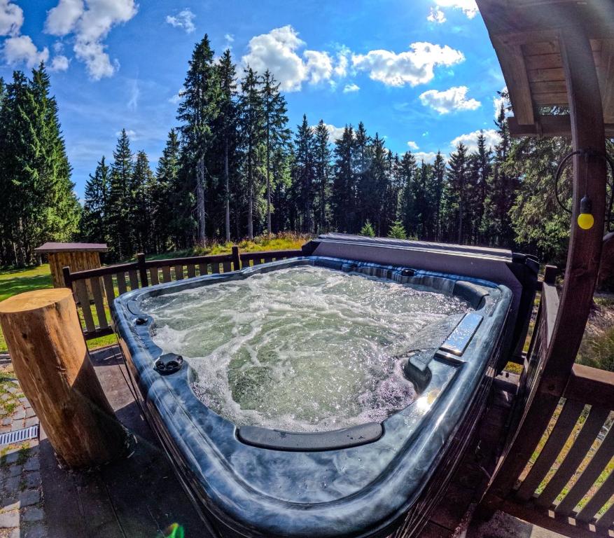 a hot tub on a deck with trees in the background at Natura Haziko in Izvoare