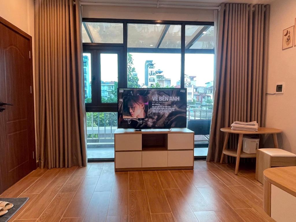 a living room with a tv and a large window at The Rose House-Lakeview Long Bien in Hanoi