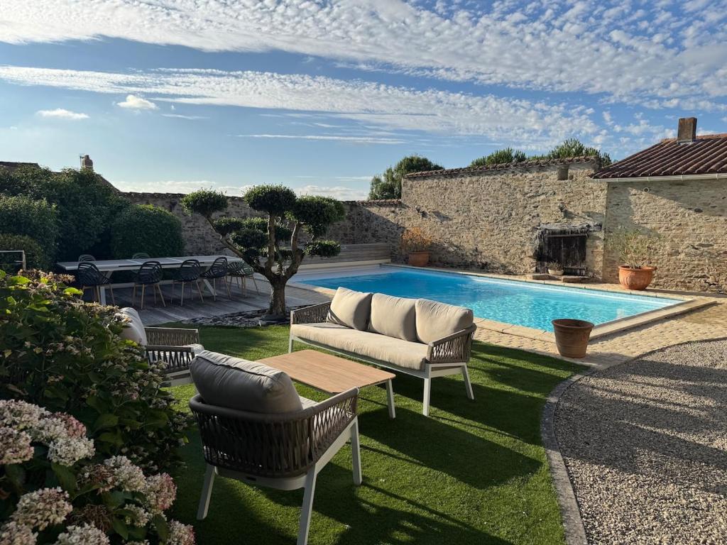 a patio with a couch and a swimming pool at Gîte L'Apothicaire in Montaigu-Vendée