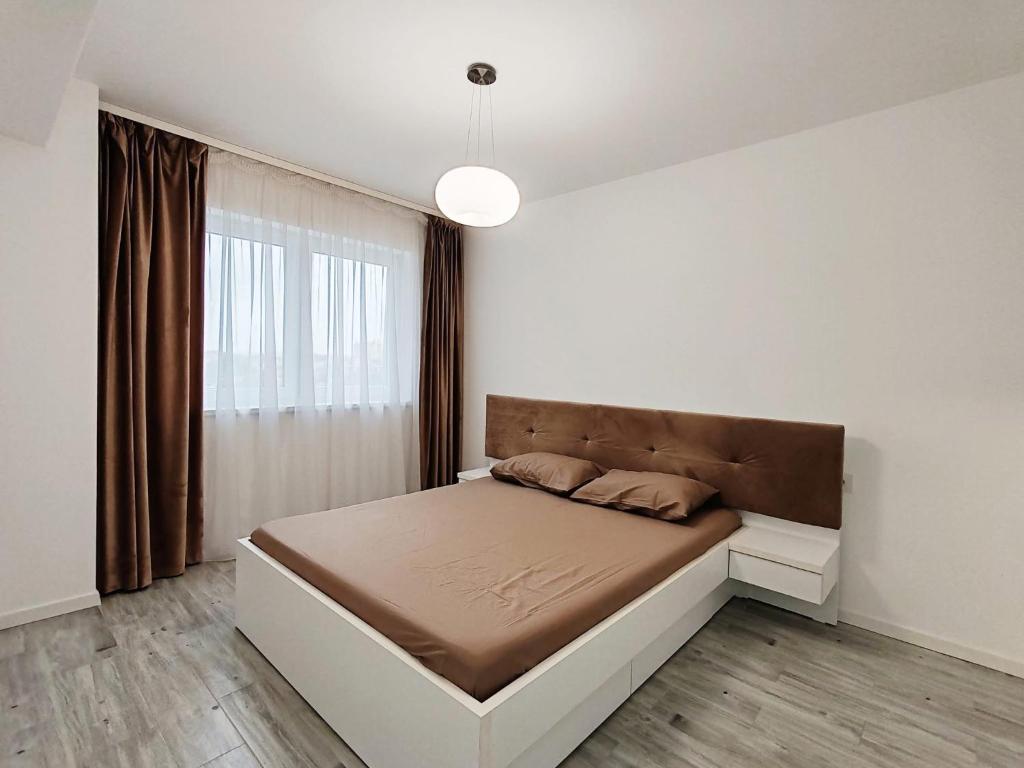 a bedroom with a bed and a large window at Emerald Apartment in Oradea