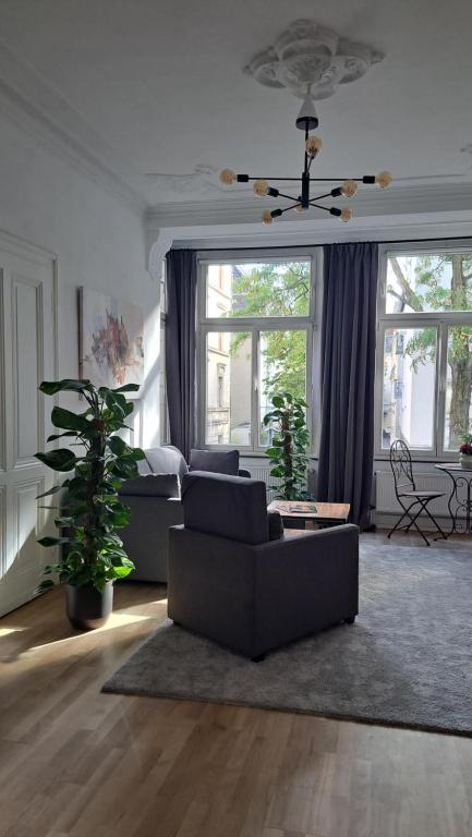 a living room with a couch and a bed and windows at Beletage Cologne in Cologne