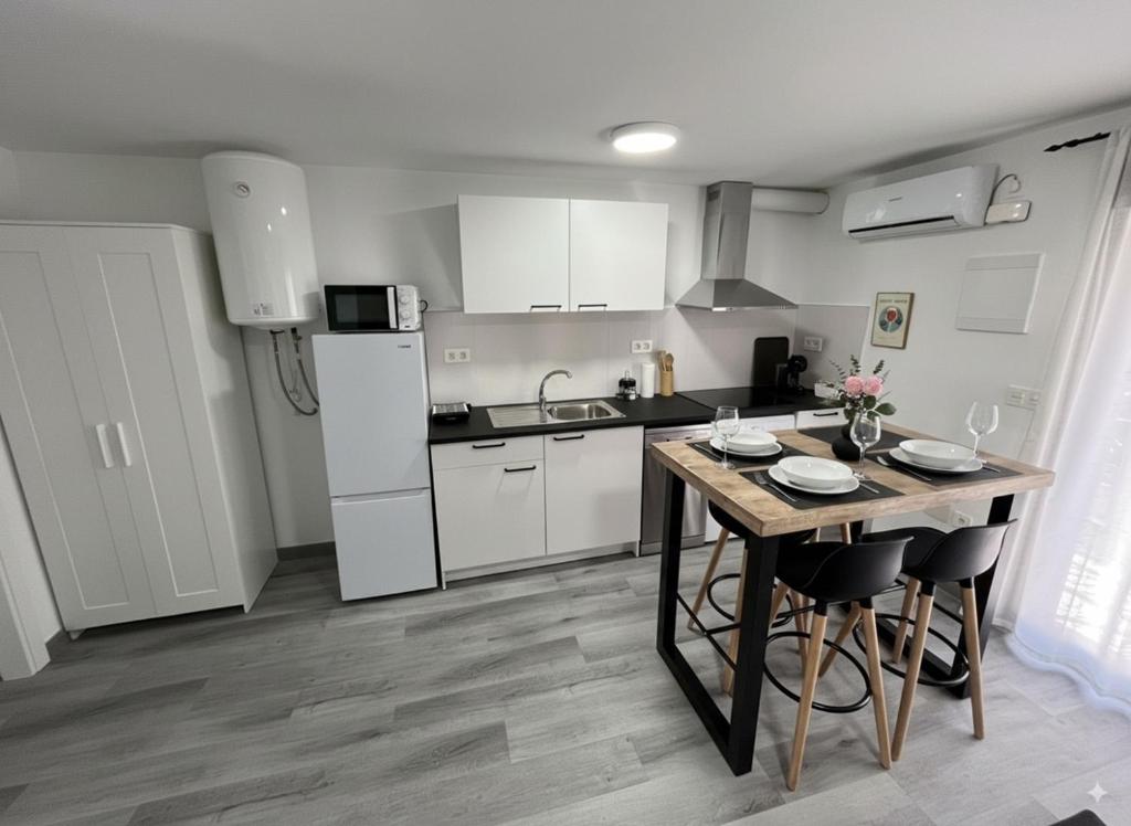 Una cocina con una mesa con sillas y un refrigerador. en Apartamentos El Savio, en Ronda