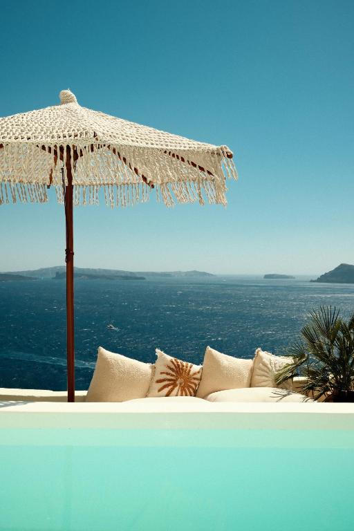 an umbrella sitting on top of a couch with the ocean at Anemos Caldera Oia in Oia