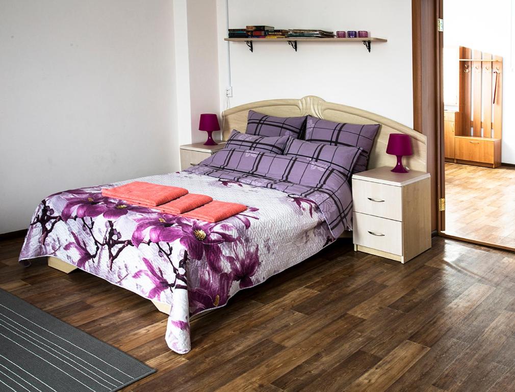a bedroom with a bed with a purple comforter and pillows at Apartments na Lenina in Nevel'