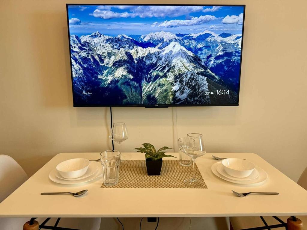 a table with plates and glasses and a tv on a wall at Makati Luxury Hotel Room Balcony Air Residence in Sampong