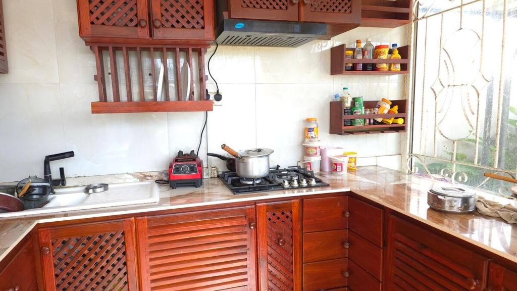 a kitchen with wooden cabinets and a stove top oven at Serenity Gardens,pool retreat, Kigamboni in Dar es Salaam