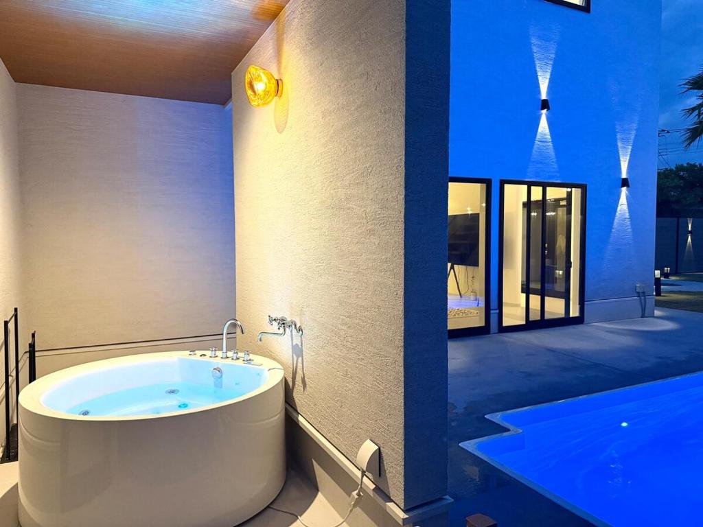 a bathroom with a bath tub next to a swimming pool at Sunshine pool villa 2新築ラグジュアリーリゾートヴィラ天然芝ゴルフサウナ完備 in Katakai