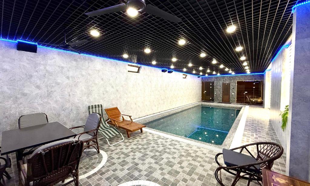 ein Pool mit einem Tisch und Stühlen daneben in der Unterkunft Mubina East Hotel in Buxoro