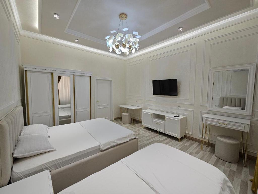 1 dormitorio con 2 camas, TV y lámpara de araña en Bobs apartments, en Samarkand