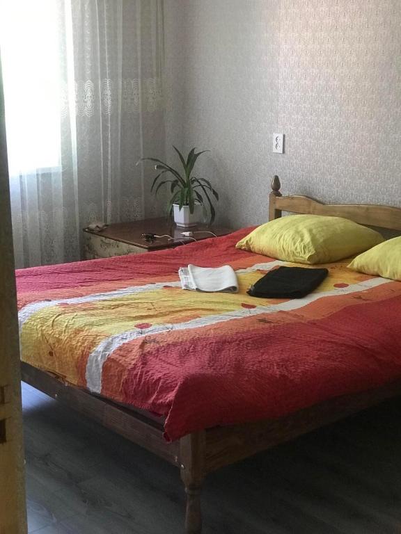 a bed with a red blanket and yellow pillows at Гарне помешкання in Uzhhorod