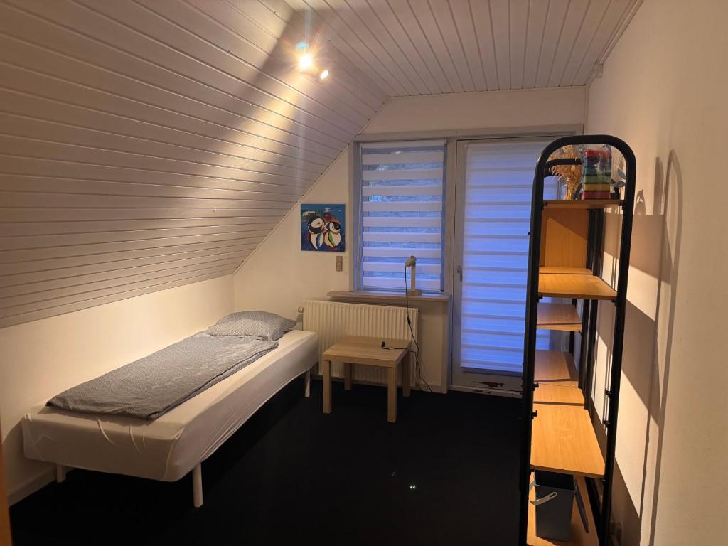a small room with a bed and a shelf at The Sunflower - Huge 240m2 7-bedroom house for 16 people - Free parking - 15 beds, 2 kitchen & 3 bathrooms in Munkebo