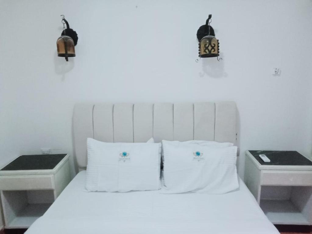 a bedroom with a white bed with two night stands at 321or322 the finest Porto Marina Chalets Tower 3 in El Alamein