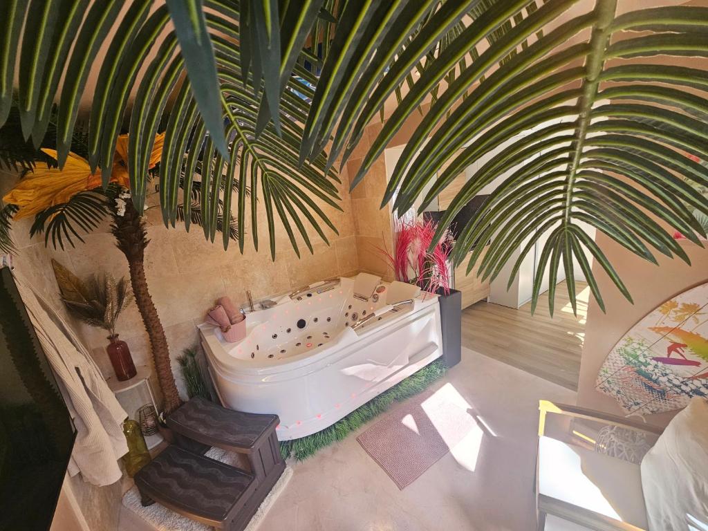 a bathroom with a bath tub and a palm tree at Oasis de bonheur avec SPA privatif à deux pas de Lille et Arras in La Bassée