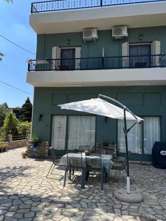 a table with an umbrella in front of a building at Kanarinia Guesthouse in Kala Nera