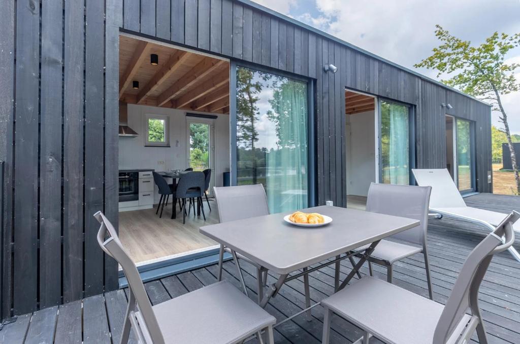 a small house with a deck with a table and chairs at Détente au golf des etoiles in Nançay