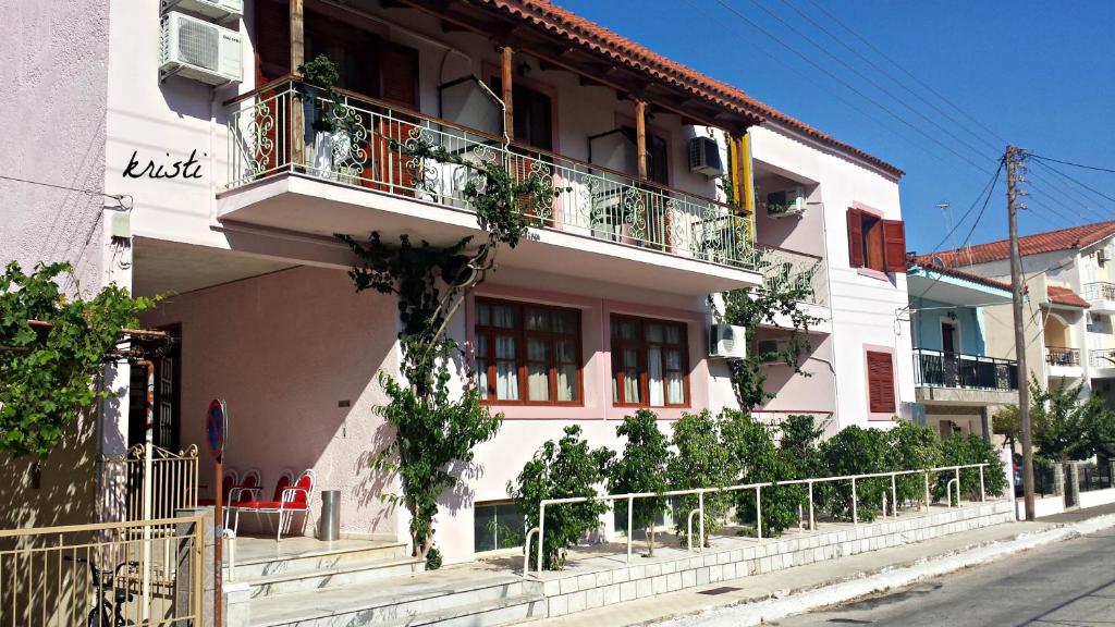 a white building with a balcony on a street at Kristi in Póros Kefalonias