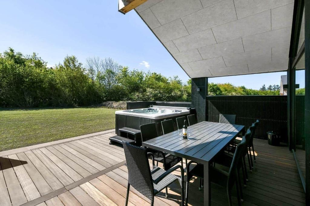 un patio con tavolo, sedie e vasca idromassaggio di C11642-Bork-Nordmarken-3 a Falen