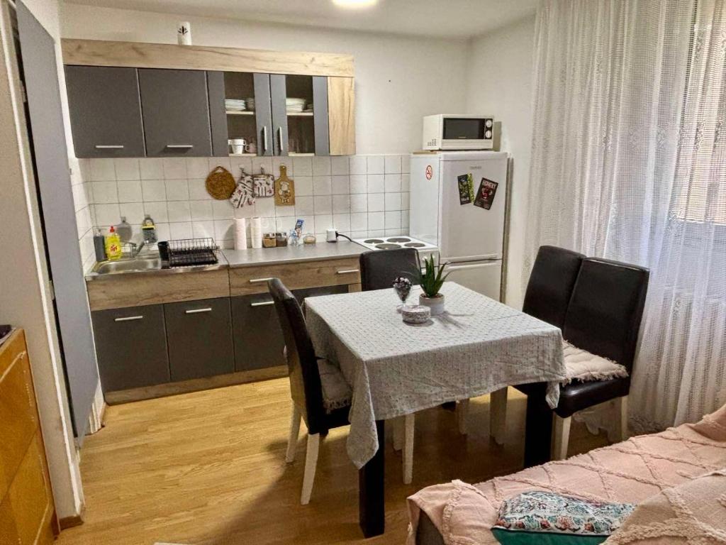 a kitchen with a table and chairs and a kitchen with a refrigerator at Apartman KEJ Smederevo in Smederevo