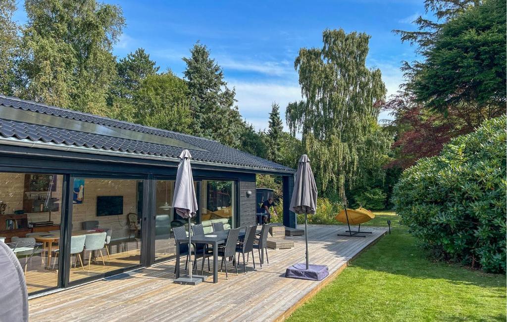 a deck with umbrellas and a table and chairs at Cozy Home In Dronningmølle With Sauna in Dronningmølle