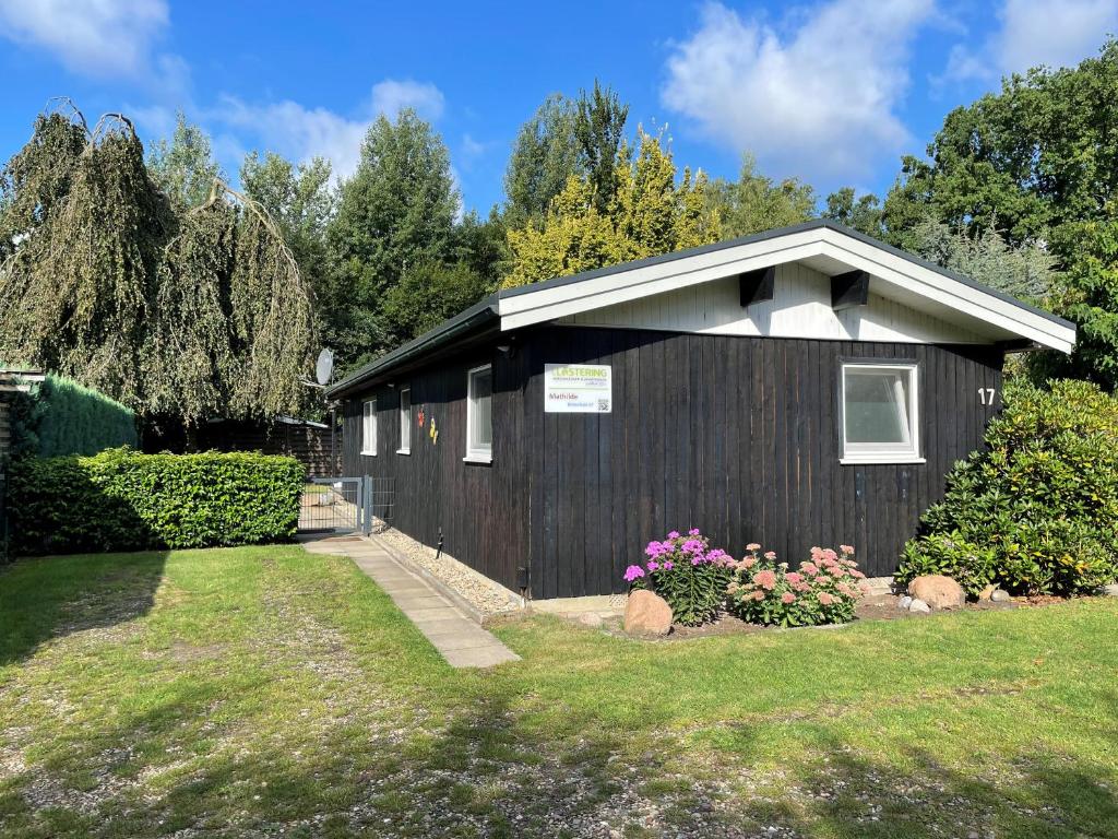 a black building with flowers in a yard at Mathilde - Lastering Ferienhäuser & Apartments in Wettringen