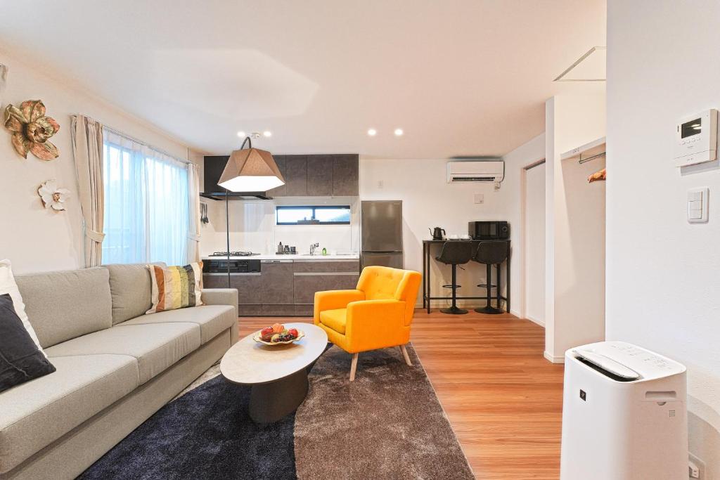 a living room with a couch and an orange chair at Tomo House 四谷三丁目 301 in Tokyo