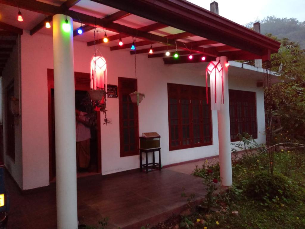 een terras met lichtjes op een wit huis bij Homestay, halpe in Badulla