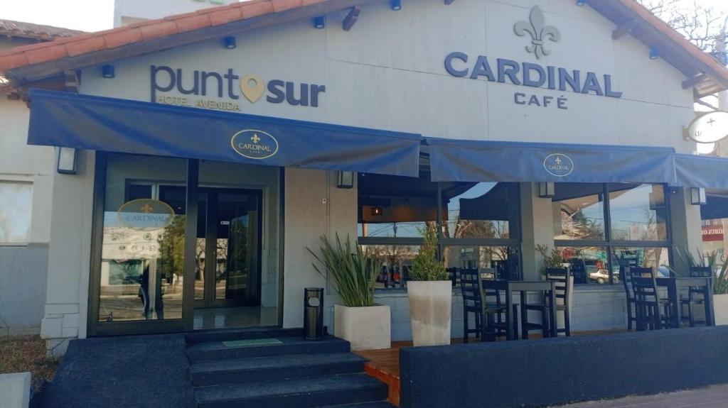 Una vista frontal de un restaurante con un toldo azul. en Hotel Punto Sur Avenida, en Malargüe