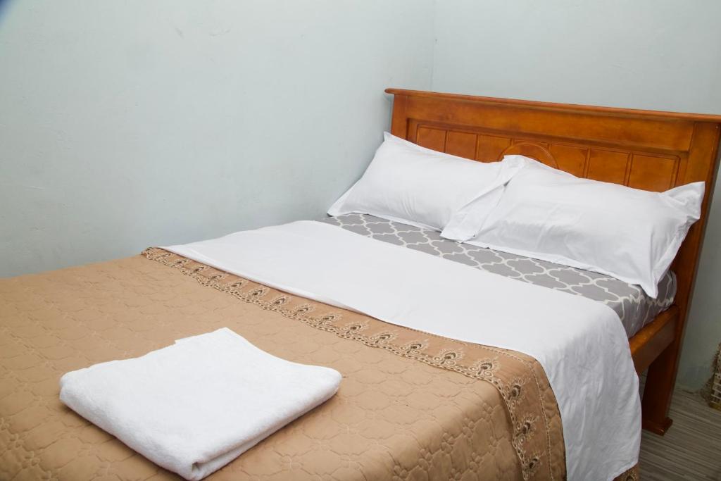 a bed with white sheets and pillows on it at The ankh guest house makidye in Kampala