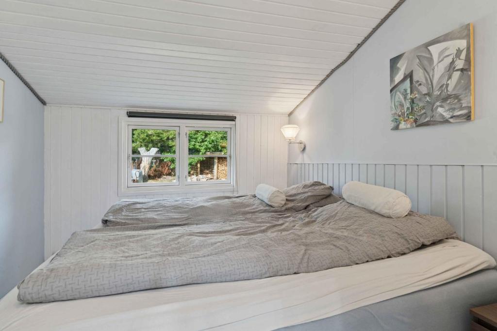 a bed in a white room with a window at Charming Cottage Close To The Beach in Glesborg