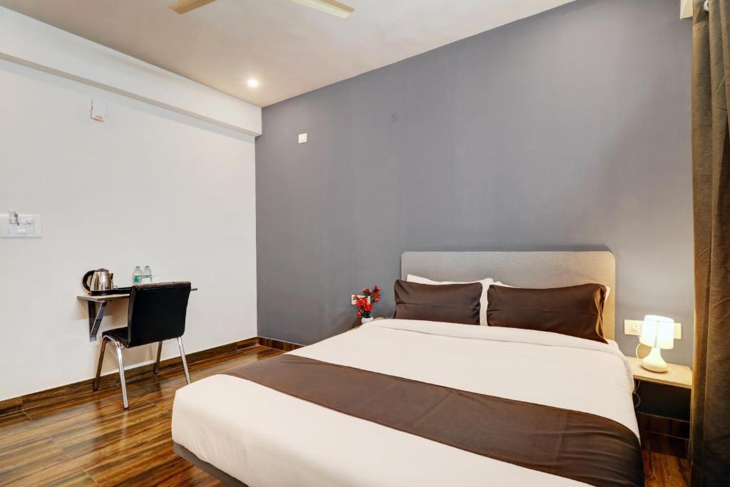 um quarto com uma grande cama branca e uma escrivaninha em Super Townhouse Ecity Inn em Bangalore