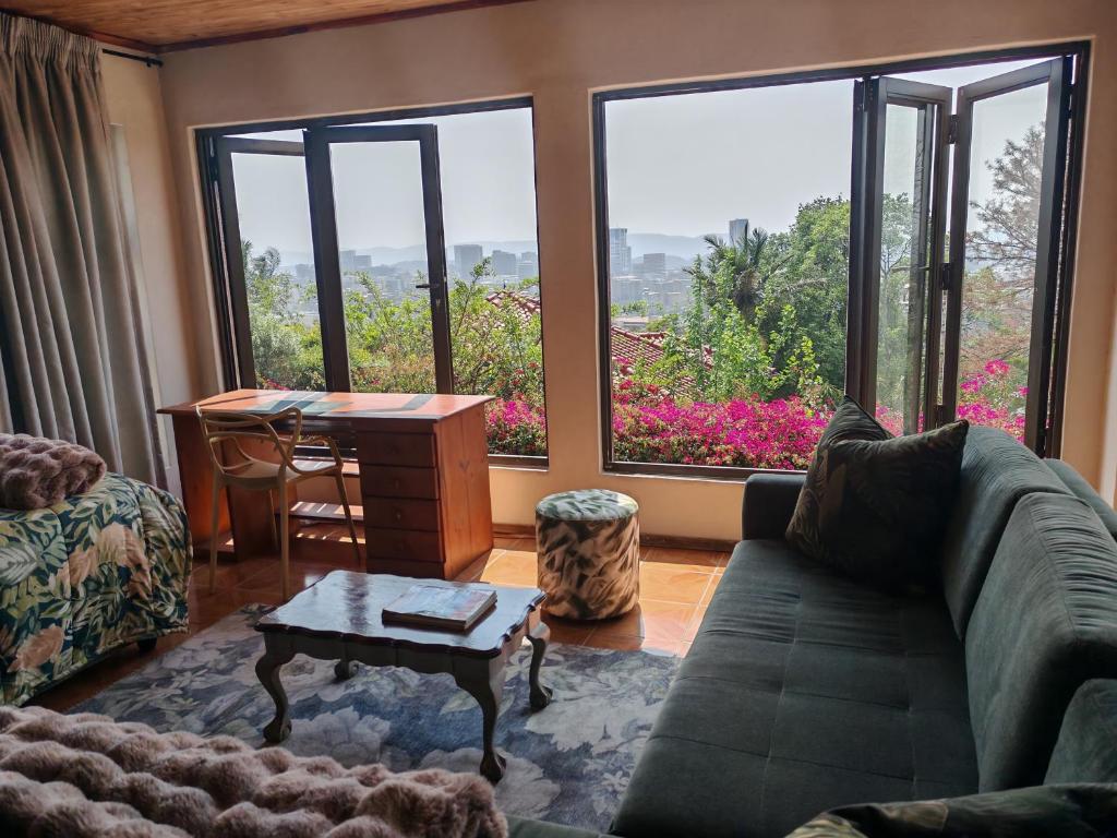 a living room with a couch and a table and windows at House Olive in Pretoria