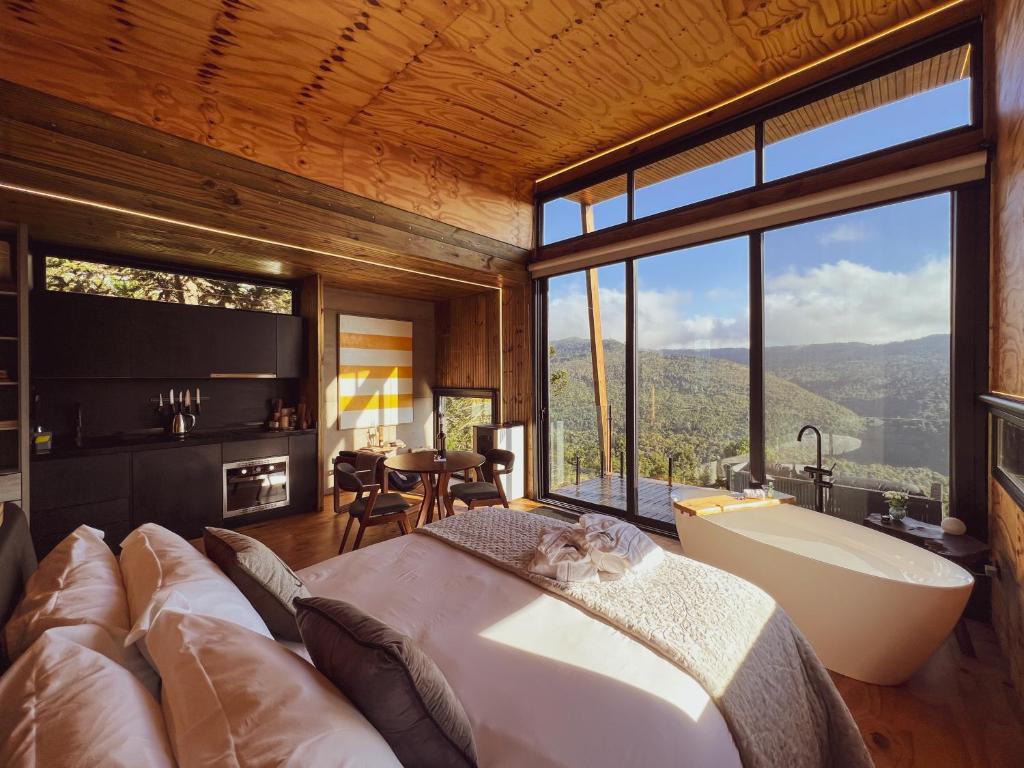 a bedroom with a large bed and a bath tub at Cabanas Terrunyo - Cabana Bela in Urubici