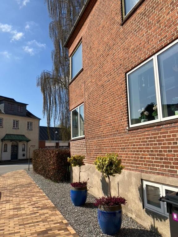 a brick building with two potted plants in front of it at Bright and spacious 3 bedroom with balcony close to the city in Aabenraa