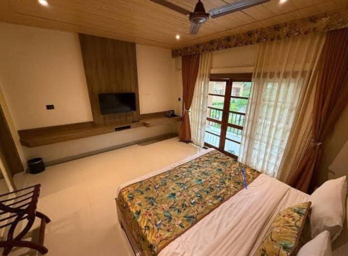 ein Schlafzimmer mit einem großen Bett und einem TV. in der Unterkunft Triptire Resort & Kaziranga in Jakhalābāndha