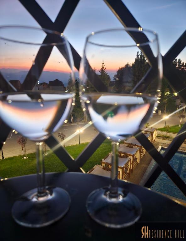 three wine glasses sitting on a table with the sunset in the background at Residence Hill Lux in Kopaonik