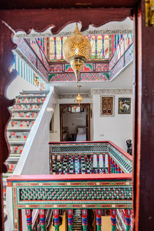 a staircase with a chandelier and colorful tile ceilings at Riad Qobbat Zaouïa in Fez