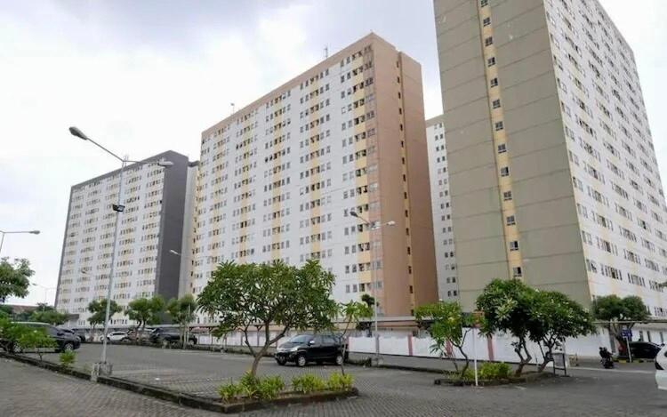 Un gran edificio con coches aparcados en un estacionamiento. en The Darmawan Room at Apartement Puncak Permai, en Mataram-baru