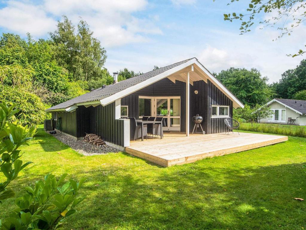 ein kleines schwarzes Cottage mit einer Holzterrasse in der Unterkunft Secluded Haven in Hvidbjerg - By Traum Ferienwohnungen in Egeskov