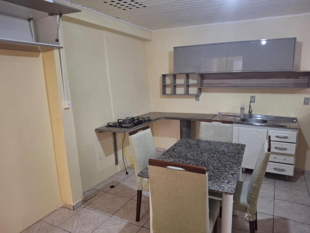 a kitchen with a table and chairs and a counter at Acomodação quarto compartilhado in Orleans