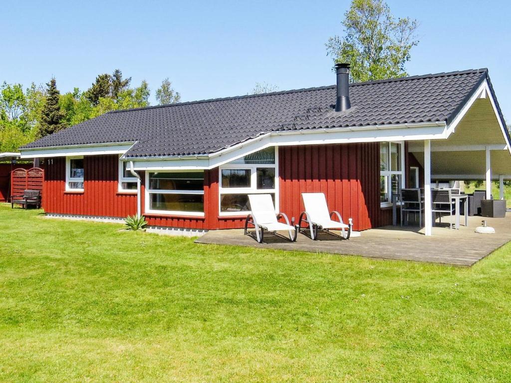 a red house with two white chairs in a yard at 4 star holiday home in Hals in Hals