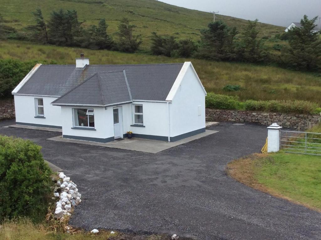 a white house with a driveway in a field at Seaview Cottage Dugort Achill Island in Doogort