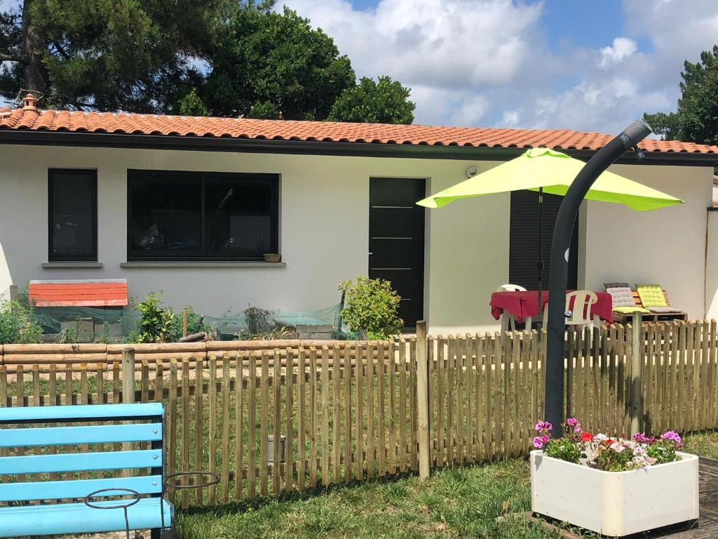 a house with a fence and an umbrella at Maison La Hume climatisée avec piscine et terrasse in Gujan-Mestras