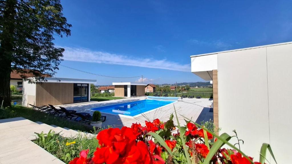a swimming pool in a yard with red flowers at Elysium2 in Banja Luka