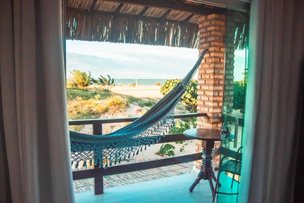 a hammock on a balcony with a view of the beach at Pousada Arte do Velejo by Solarium in São Miguel do Gostoso