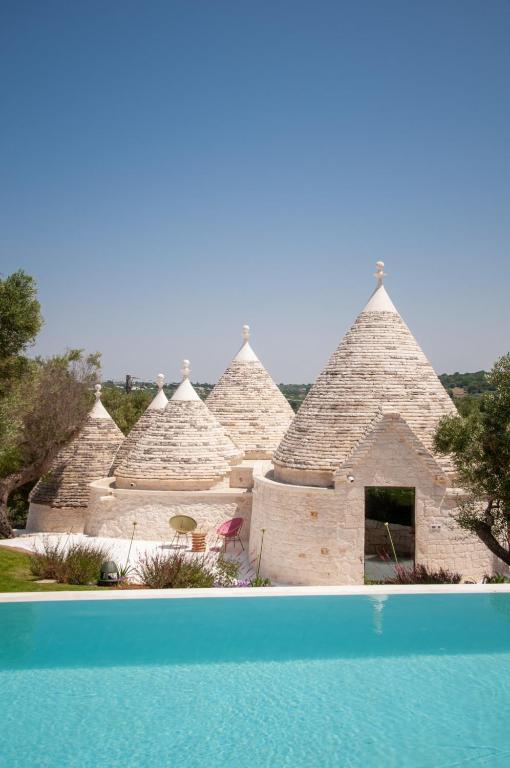 a group of pyramid shaped buildings with a swimming pool at Trulli Moranera in Cisternino