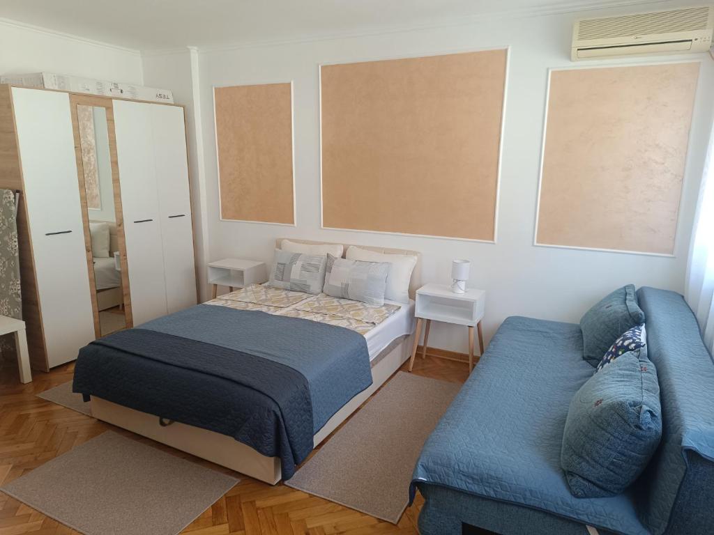 a bedroom with a bed and a blue couch at Apartman Nicolas in Karaburma