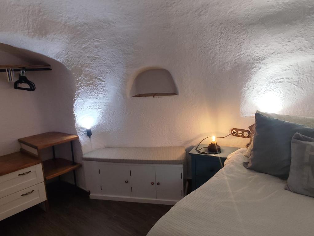 a bedroom with a bed and a table with a lamp at Cueva la estrella in Chinchilla de Monte Aragón