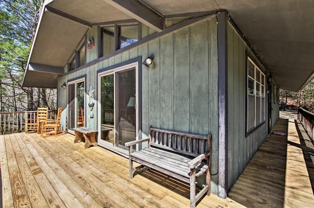 a green house with a bench on a wooden deck at Modern Rustic Cabin - Cozy Forest Escape in Gatlinburg