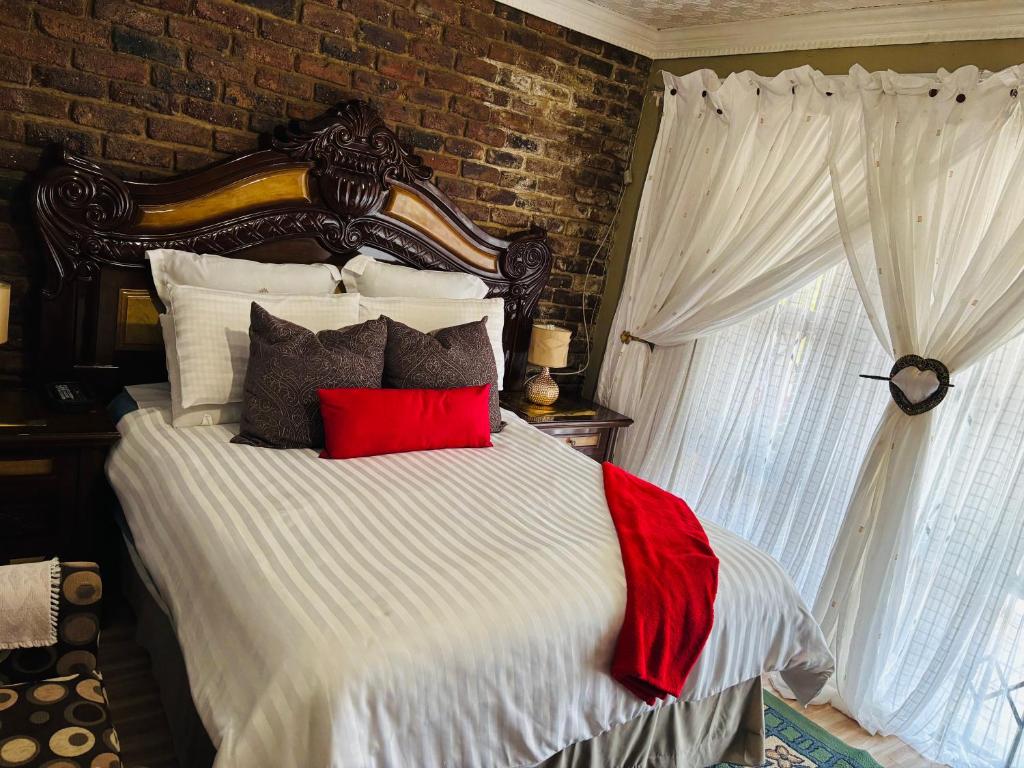 a bedroom with a large bed with red pillows at Nalana Guest House in Thaba Nchu